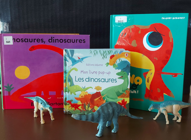 Dinosaures positionnés devant des livres jeunesses