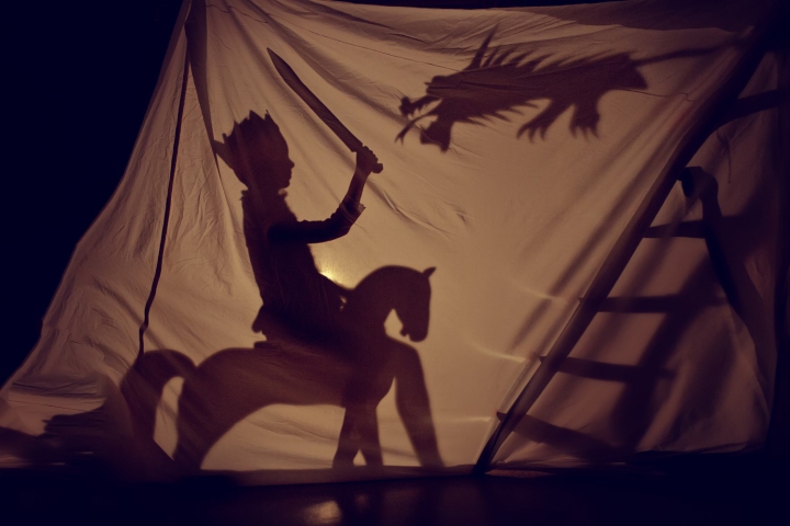 photographie d'un théâtre d'ombre en action : un cavalier couronné fait face à un dragon