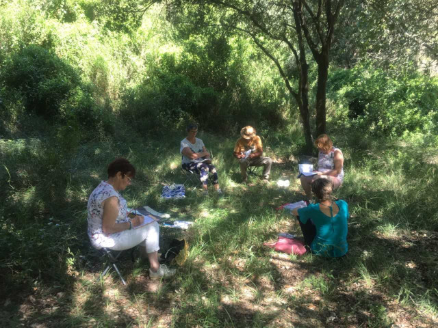 5 personnes assises dans la nature en train d’écrire