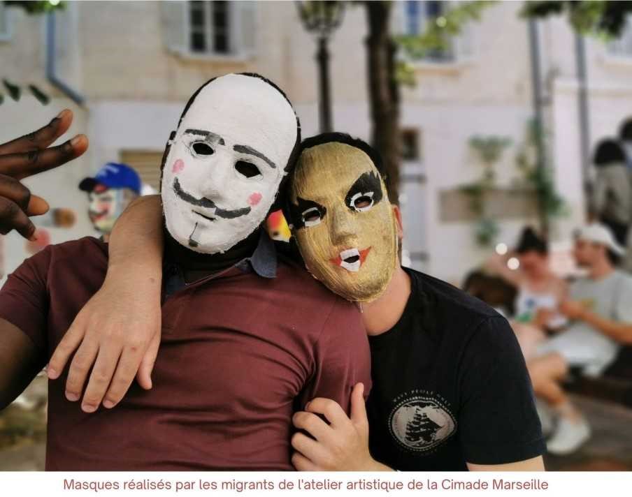 Deux hommes avec des masques fabriqués lors d'ateliers réalisés par la CIMADE