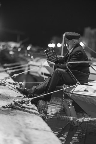 Un marin lit un polar sur son bateau au miroir aux oiseaux