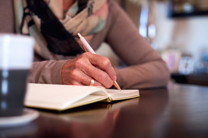 picture of someone writing on a notebook on a counter