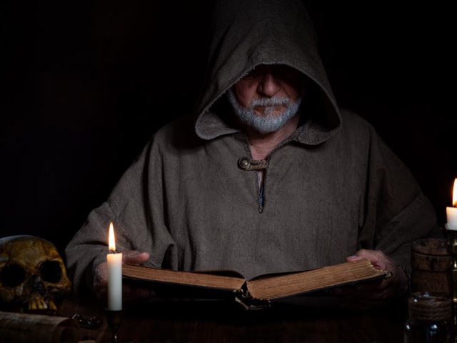 Homme lisant un livre à la lueur d'une chandelle