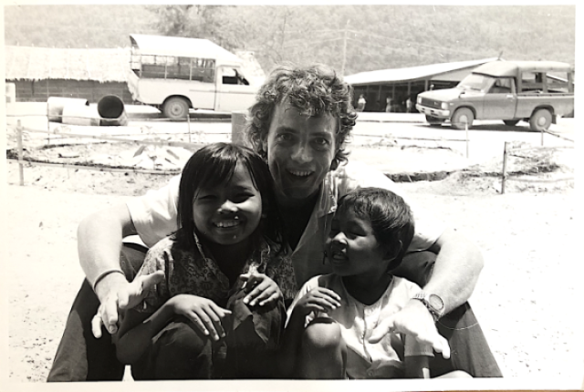 Photo en noir et blanc avec Eric Bouhier au milieu tenant deux enfants par les épaules