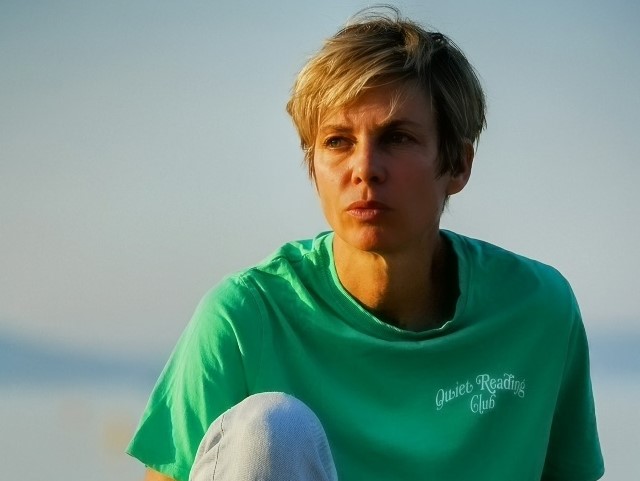 Image de Sigolène Vinson regardant au loin, en t-shirt vert et jean 